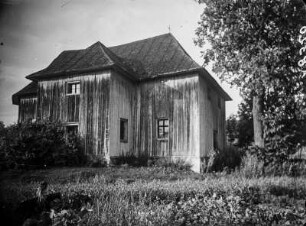 Holzkirche : Blick über eine Wiese auf ein Holzgebäude, vermutlich eine Kirche.