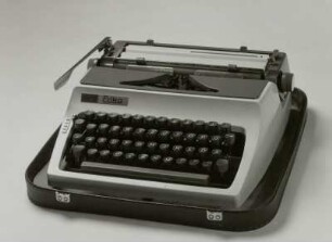 Typenhebelschreibmaschine "daro Erika" (Modell 32). Vorderanschlag (sofort sichtbare Schrift), Universaltastatur, Farbband, Koffermaschine. Schrägansicht von vorn