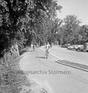 Lübecker Straße / B 75: Parkplatz vor Schloss, Autos: Fahrradweg, Fahrradfahrer: Familie auf Fußgängerweg: hinten links Geländer zur Schlossbrücke: hinten Telefonzelle