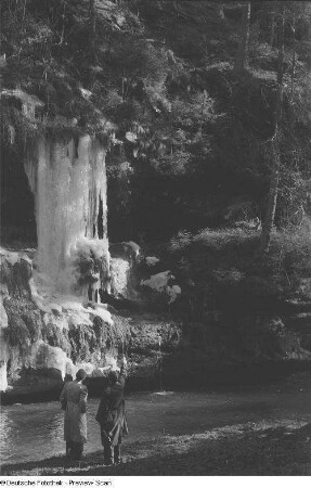 Zwei Wanderer beim Betrachten von großen Eiszapfen