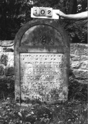 Grabstein 102 (Index: 100110763) Material: Sandstein Zustand: leicht verwittert mit kleinen Abschieferungen Maße HxBxT: 122x74x11 cm Beschreibung: Stele, Rundbogenabschluß, Schriftfelder eingetieft: Grabstein 102