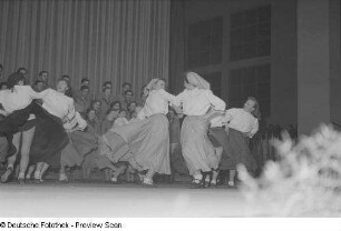 Tanzende junge Frauen bei einer Kulturveranstaltung in Halle II, im Hintergrund ein Chor