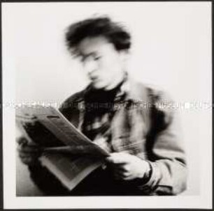 Verschwommenes Bild eines Zeitung lesenden jungen Mannes (Sonderthema: Ein Bild von mir - Selbstporträts und Selbstdarstellungen)