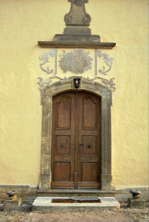 Westportal Kirche mit barocken Stuckverzierungen und Inschriftstein