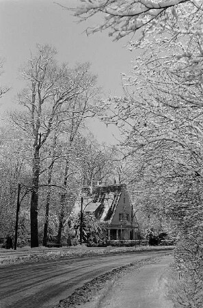 Winter in Leipzig, Blick in eine Straße und den verschneiten Giebel eines Hauses, davor eine Bushaltestelle