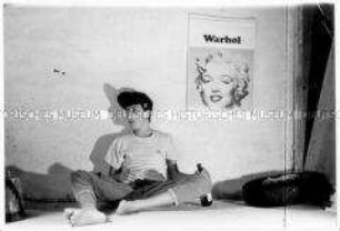 Sitzender, rauchender Jugendlicher neben einem Andy-Warhol-Plakat (Altersgruppe 14-17)