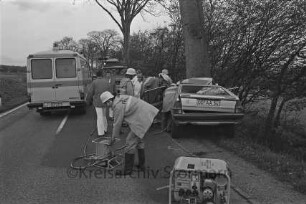 Stadtrand: Verkehrsunfall mit einem Toten: Pkw gegen Baum: in der Mitte Rettungskräfte: links Rettungswagen: im Hintergrund Feuerwehrfahrzeug: vorne rechts Generator