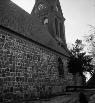 Martin-Luther-Kirche: Außenansicht: vor Sockel Erdarbeiten: hinten rechts Eisenträger an Wand: darüber kleines Holzgerüst auf Dach: hinten Bäume