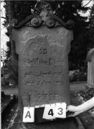 Grabstein 43 (Index: 99792824) Material: Sandstein Zustand: sehr stark verwittert mit Textverlust Maße HxBxT: 135x45x28 cm Beschreibung: Stele, seitlich profiliert, oben Erweiterungen, Volutengiebel mit Akroter: Grabstein 43A