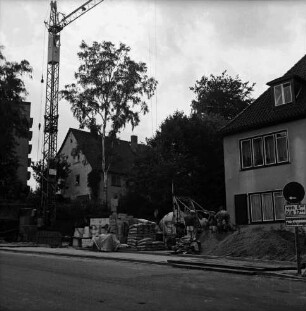 Sülzberg: in der Mitte Baustelle mit Ziegelstapel, Zementsäcken, Baumaschinen, Erdhaufen: dazwischen Arbeiter: hinten rechts und links Wohnhäuser: hinten links Baukran und Hochhaus