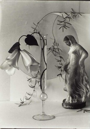 "Blumen um uns" (Photographische Plaudereien in Wort und Bild). Stilleben mit Lilienzweig in Glasvase und Keramikfigur (Schreitendes Mädchen)