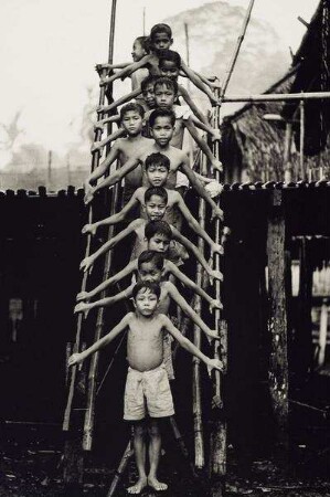 Kinder des Iban-Stammes auf einer Leiter vor ihrem Langhaus, Sarawak, Borneo, Malaysia, 1964