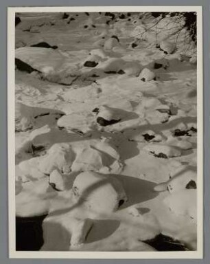 Winter. Zugefrorener Bach. Die Steine im Bach sind mit Schnee bedeckt