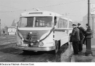 Personen betrachten einen mit Girlanden geschmückten Omnibus H6B