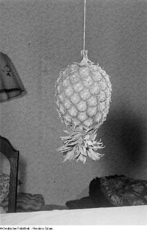 Eine an einem Band befestigte Ananas hängt über einem Tisch