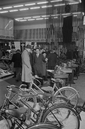 Messebesucher in der Ausstellungshalle Polens und Ungarns vor einer Präsentation von Fahrrädern und Nähmaschinen