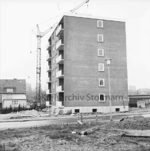 Am Kurpark: Wohnblock vor Fertigstellung: links Baubude, Baukran und Wohnhaus: davor unbefestigtes Gelände mit Baumaterial und Sandhaufen: rechts flaches Gebäude: hinten rechts weitere Gebäude