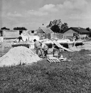 Dienstleistungszentrum: Oetjendorfer Kirchenweg / Am Schwarzen Berg: Bau: vorn links Sandhaufen: daneben Arbeiter an der Mischmaschine: hinten weitere Arbeiter auf Fundament: hinten Grundmauern: dazwischen Baumaterial: hinten Einfamilienhäuser nach Fertigstellung und im Rohbau