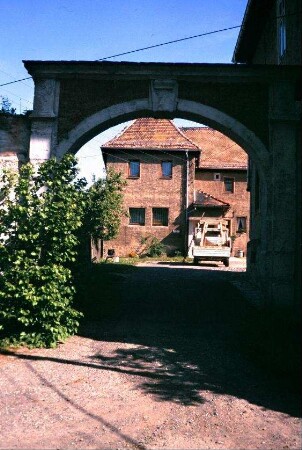 Blick durch einen steinernenn Torbogen in einen Hof