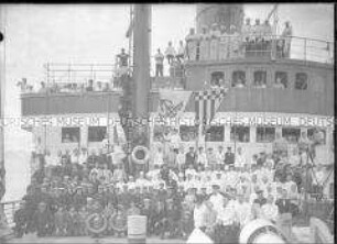 Gruppenfoto von Kapitän und gesamter Besatzung des Hochseepassagierdampfers "Berlin" unter der Handelsflagge des Norddeutschen Lloyd