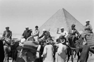 Touristen : Eine Gruppe Touristen beim Aufsitzen auf Kamele vor der Cheops-Pyramide.