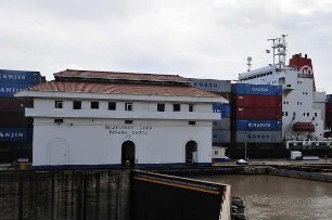 Gebäude der Zentrale der Miraflores-Kanalschleuse : Am 80 km langen Panama-Kanal vom Atlantik zum Pazifik können Besucher in der Miraflores-Schleuse die Durchfahrt großer Containerschiffe beobachten. Bild: Schleusenzentrale mit Containerschiff aus China im Hintergrund. Aufgenommen am 15. September 2011