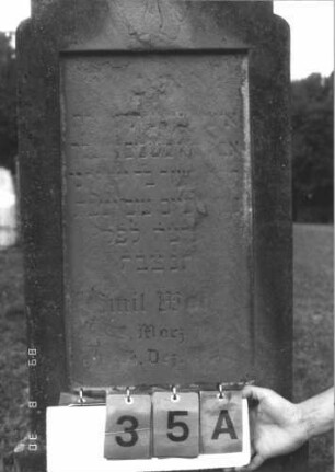 Grabstein 35 (Index: 99609671) Material: Sandstein Zustand: stark verwittert, weitgehender Textverlust Maße HxBxT: 153x48x19 cm Beschreibung: Stele, eingezogener Konvexbogenabschluß, Schriftfeld rechteckig eingetieft, getreppter Sockel, unten Rusticaimitat Symbolik: segnende Hände: Grabstein 35A