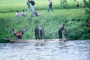 Flößer mit langen Stangen am Ufer der Saale