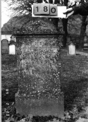 Grabstein 180 (Index: 99798612) Material: Sandstein Zustand: gut Maße HxBxT: 112x46x9 cm Beschreibung: Stele mit Rundbogenaufsatz und seitlichen Akrotzeren, Sockel Symbolik: gekreuzte Palmzweige: Grabstein 180