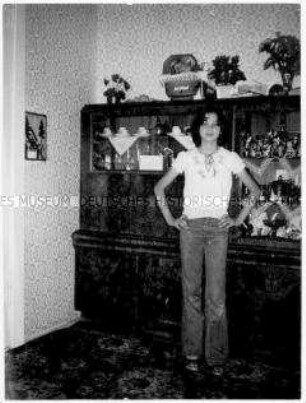 Junges Mädchen posiert vor einem Wohnzimmerschrank (Altersgruppe bis 14)