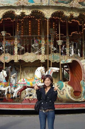 Chinesische Touristin läßt sich vor einem historischen Karussell am Montmartre fotografieren