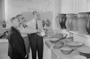 Mehrere Personen begutachten an einem Stand mit Steingutwaren auf der Leipziger Herbstmesse 1955 eine Schale