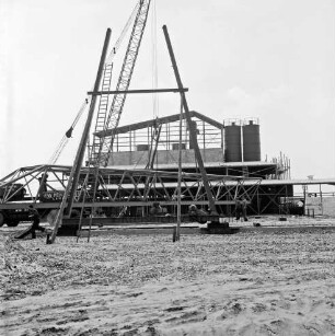Hartsteinwerk: Rohbau: links Kranwagen mit Ausleger: daran Brückenteil einer Laufkatze: vorn und hinten Mitte Ständer: hinten Werkhalle im Aufbau