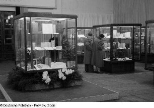 Besucher betrachten die in Vitrinen ausgestellten Exponate bei der 2. Deutschen Buchkunst-Ausstellung