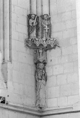 Heiligenfigur unter einem Baldachin, darüber zwei Apostelfiguren