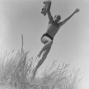 Mann in Badehose springt am Strand