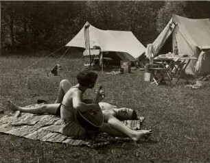 Auf einem Zeltplatz. Eine junge Frau spielt Mandoline