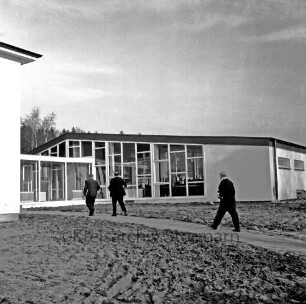 Franz-Spliedt-Heim: Jugendheim des Deutschen Gewerkschaftsbundes (DGB-Nordmark): Seebergen: Erweiterungsbau mit Lehrsaal und Bettenhaus vor Fertigstellung: vorn unbefestigte Außenanlagen: drei Männer auf dem Weg ins Gebäude