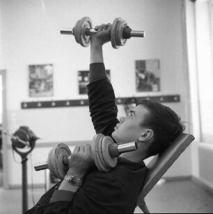Lehrling während des Sportunterrichtes beim Krafttraining mit Hanteln