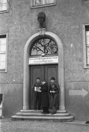Berlin-Dahlem. Freie Universität Berlin. Rechts- und Wirtschaftswissenschaftliche Fakultät. Studenten vor dem Eingang (Der Eingang des ersten Gebäudes der zunächst gemeinsamen Rechts- und Wirtschaftswissenschaftlichen Fakultät, später - ab dem Sommersemester 1949 - der Eingang zur Juristischen Fakultät. Heute wird das Gebäude in der Ihnstraße 22 vom Otto-Suhr-Institut der Freien Universität genutzt)