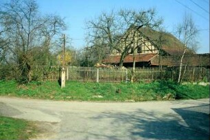 unbefestigter Weg, Gartenzaun und dahinter Giebelansicht einer Fachwerkscheune