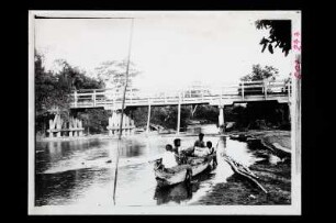 Holzbrücke in Südthailand : Südthailand. Hölzerne Brücke über einen Fluss, im Vordergrund mit Personen besetztes Boot am Ufer, 1912/1913