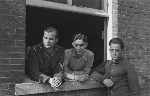 Zweiter Weltkrieg. Niederlande unter deutscher Besatzung. Drei deutsche Wehrmachtsangehörige an einem Fenster (wohl bei Den Haag)
