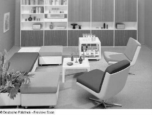 Vier Hocker und zwei Drehstühle mit Beistelltisch, Barwagen und Blumenkasten : Leipziger Herbstmesse, 1973. Möbelprogramm "variopur" (1973; VEB Petrolchemisches Kombinat Schwedt). Vier Hocker und zwei Drehstühle mit Beistelltisch, Barwagen und Blumenkasten vor Anbauwand