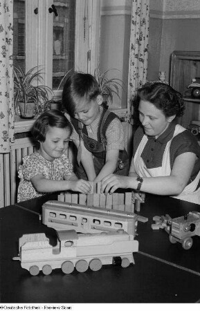 Porträt einer Kindergärtnerin beim Spielen mit Kindern
