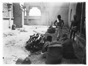 Varanasi (Benares), Indien. Verbrennung eines Hindu an öffentlicher Verbrennungsstätte. Blick in eine Halle mit Arkadenöffnungen und Säulen, an deren Boden Verbrennungsstellen sind