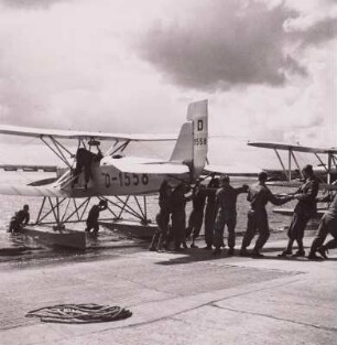 Rostock-Warnemünde. Deutsche Verkehrsfliegerschule, Zweigstelle Seefliegerschule Warnemünde. See-Schulflugzeug Heinkel HD-24b mit der Kennung D-1558 wird nach der Wasserung von einer Mannschaft an Land gezogen