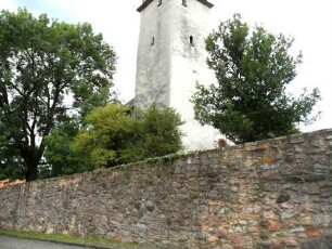 Ansicht von Südwesten mit Kirchturm (im Kern 13 Jh-im 18 Jh überarbeitet) über Kirchhofmauer (Wehrgang mit Steinbrüstung im 18 Jh abgetragen) von Ortsseite