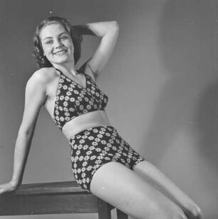 Frau im Bikini sitzt auf einem Tisch