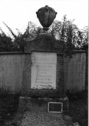 Grabstein 8 (Index: 99936893) Material: Granit, weiße Marmorplatte Zustand: Platte mehrfach gesprungen Maße HxBxT: 189x69x33 cm Beschreibung: konische Stele, Sockel, giebelartiger Abschluß mit Aufsatz, rechteckige Schriftplatte Symbolik: Urnenaufsatz: Grabstein 8